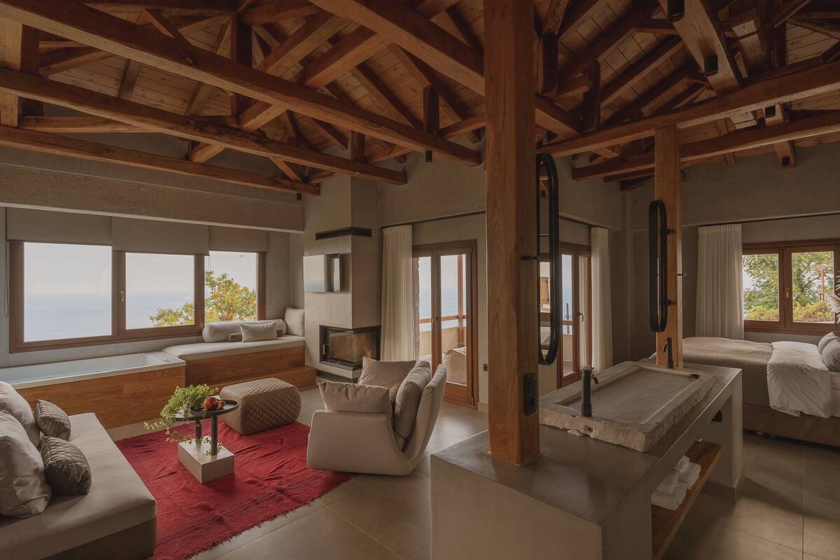 A spacious room with a high ceiling, large windows, a fireplace, and a cozy seating area.