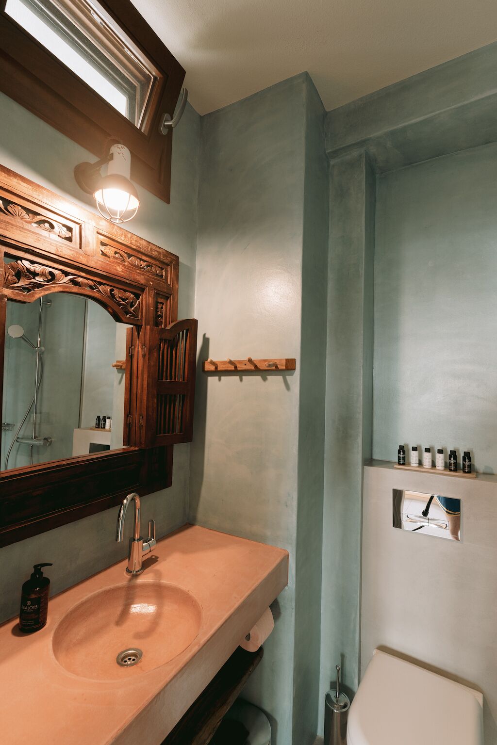 A bathroom with a wooden vanity, a large mirror, a sink, and a toilet.