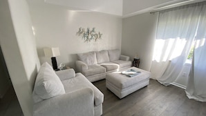 A living room with a sofa, ottoman, and a decorative wall piece.