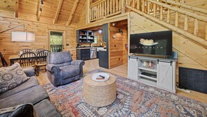 A cozy log cabin interior with a living room, dining area, kitchen, and a staircase. - Cozy Mountain Cabin w/ Hot Tub Close to Gatlinburg (Sevierville)