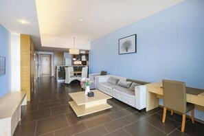A modern living room with a sofa, coffee table, and a dining area with a table and chairs. - Yimi Yangguang Seaview Holiday Apartment (Huidong)