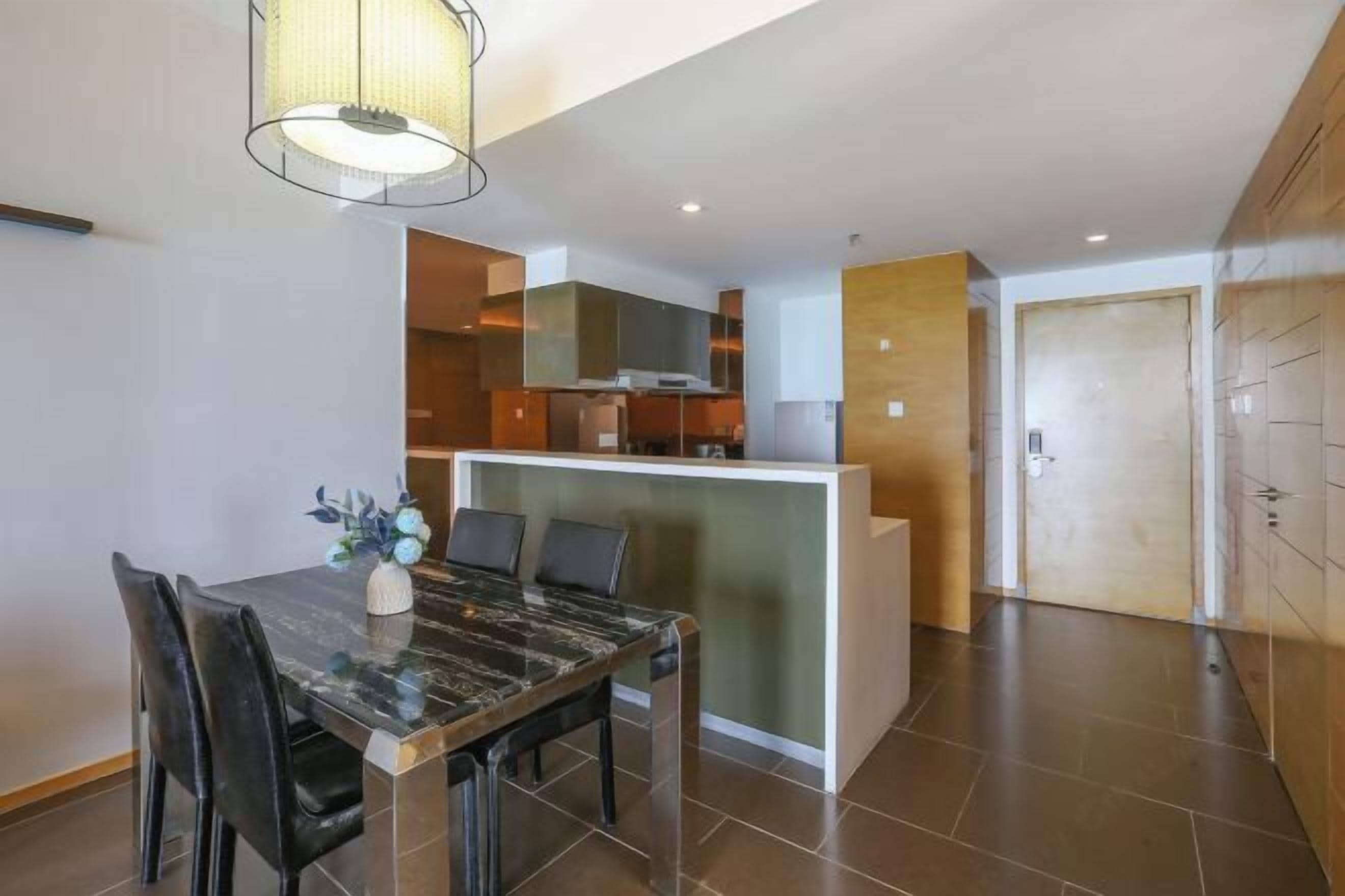 Una cocina moderna con una isla central, un comedor con una mesa de mármol y vista al área de estar.
