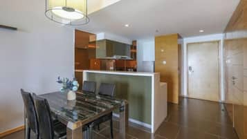 Una cocina moderna con una isla central, un comedor con una mesa de mármol y vista al área de estar.