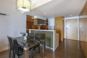 A modern kitchen with a central island, a dining area with a marble table, and a view of the living area. - Yimi Yangguang Seaview Holiday Apartment (Huidong)