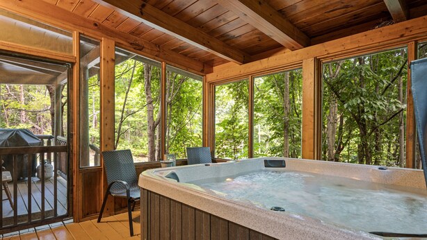 Eine Holzterrasse mit Whirlpool, Stühlen und Tisch.