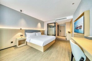 Et moderne hotelværelse med en stor seng, sengeborde, et skrivebord og et spejl.