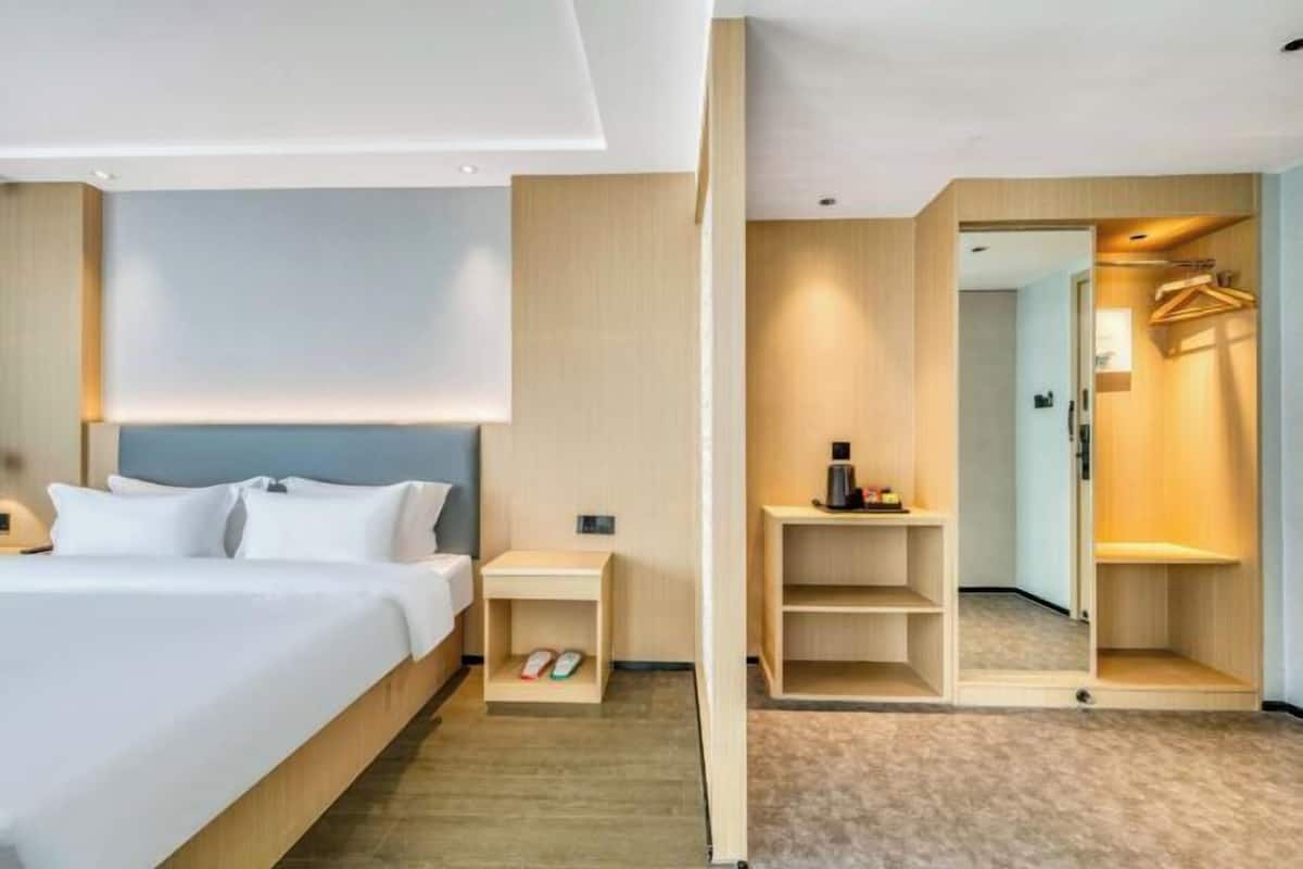Een hotelkamer met een bed, nachtkastje en een inloopkast met spiegel.