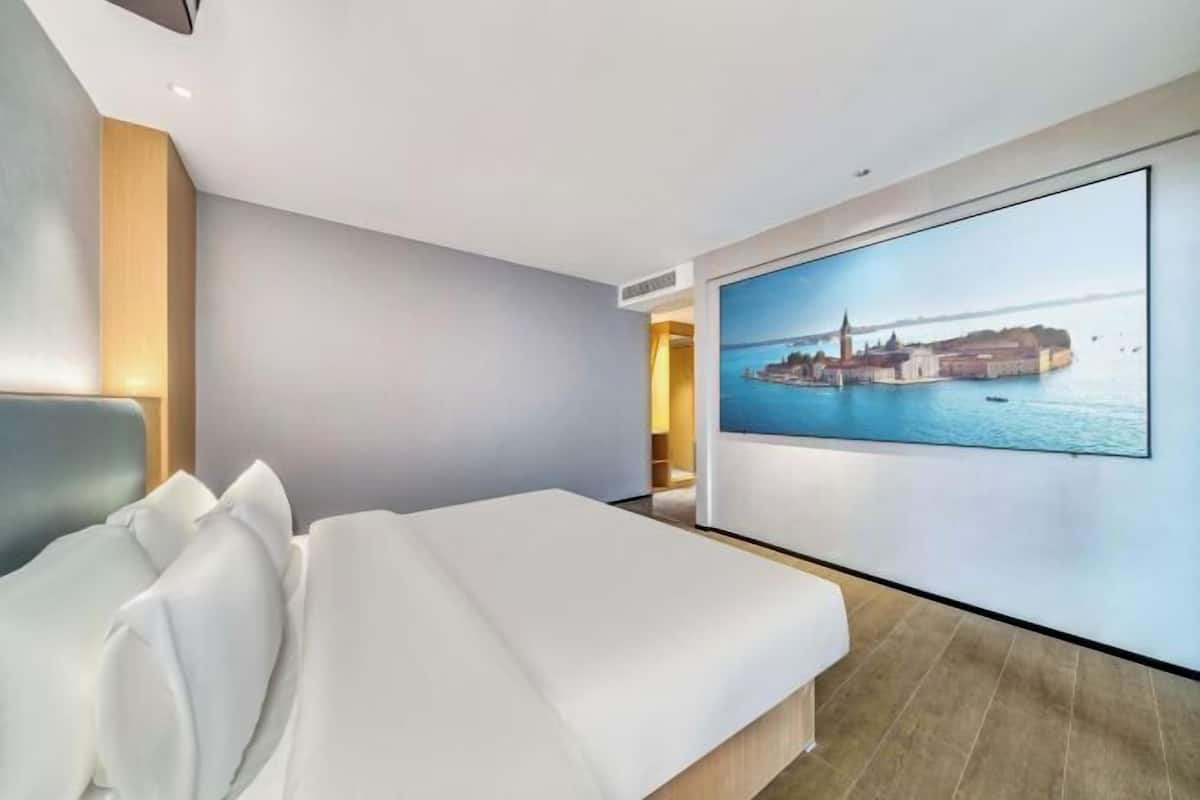 Een moderne hotelkamer met een groot bed, een aan de muur bevestigde televisie en uitzicht op de stad.