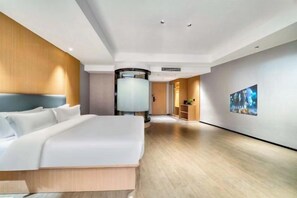 Una habitación de hotel moderna con una cama grande, un espejo redondo y un pasillo con obras de arte.