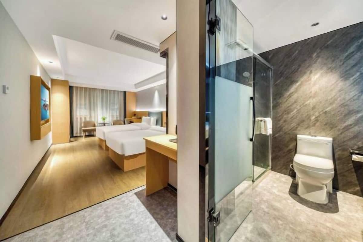 Een moderne hotelkamer met een bed, bureau en een douchecabine van glas.