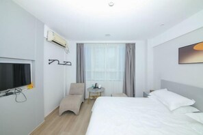 A hotel room with a bed, a chair, a TV, a table, and an air conditioning unit. - Yueqing Yuecheng Donghai Holiday Hotel (Yueqing)