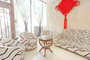 Um quarto com sofás estampados, uma mesa redonda e um objeto decorativo vermelho na parede.