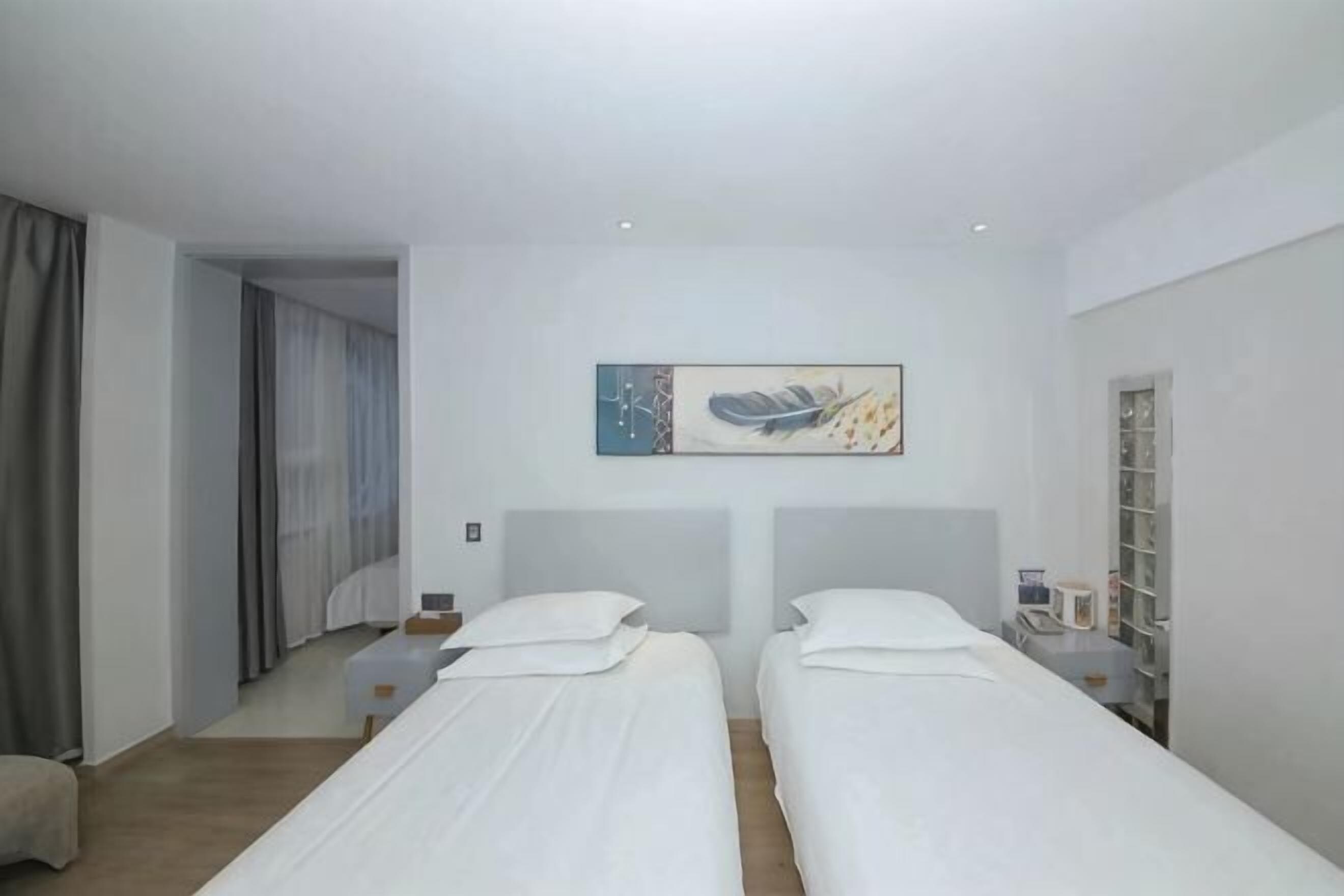Quarto de hotel com duas camas, um quadro na parede, uma escrivaninha e um guarda-roupa.