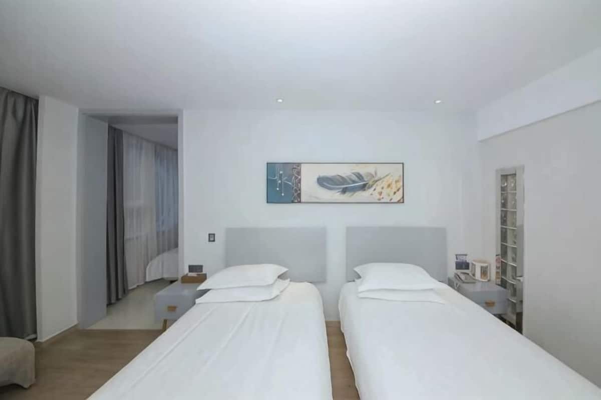 Ein Hotelzimmer mit zwei Betten, einem Bild an der Wand, einem Schreibtisch und einem Kleiderschrank.