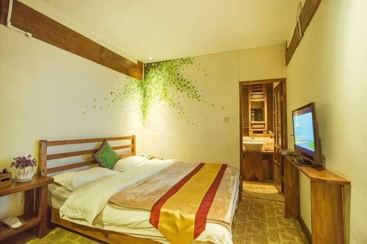 A bedroom with a bed, bedside table, TV, and a wall-mounted plant.