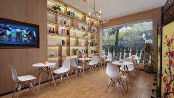 A modern interior with a wooden floor, white chairs, a bookshelf, and a television screen.
