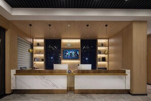 A reception desk with a marble counter, two white chairs, and a television screen. - Qingyi Hotel (Taizhou)