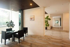 A hotel lobby with a dining area, a staircase, and potted plants. - Aizhihai (Beihai)