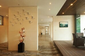 A hotel lobby with a long reception desk, a wall-mounted sculpture, and a framed picture. - Aizhihai (Beihai)