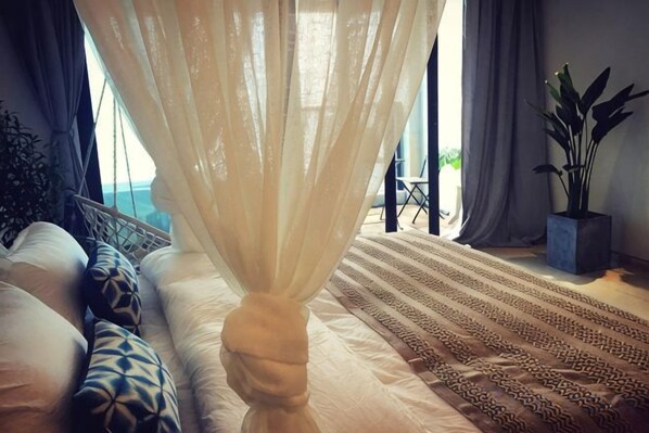 A bedroom with a bed, a hanging chair, a potted plant, and a view of the outdoors. - Aizhihai (Beihai)
