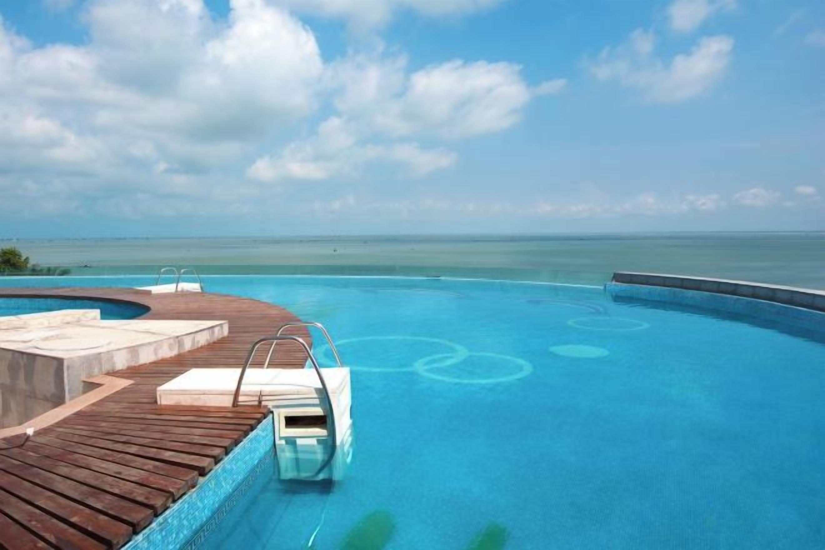 Une piscine avec une terrasse en bois et vue sur l’océan.