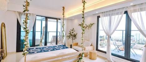 A modern bedroom with a large bed, large windows, and a balcony view.