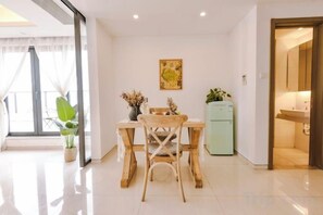 Un coin repas avec une table et des chaises en bois, un réfrigérateur et une plante en pot.