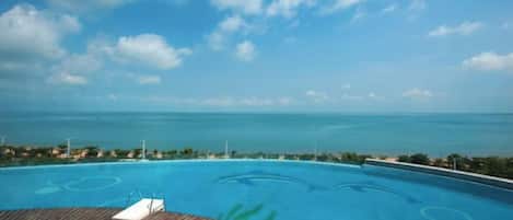 A pool with a wooden deck and a view of the ocean.