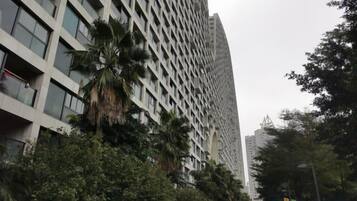 A tall building with a grid-like facade, surrounded by trees and greenery.