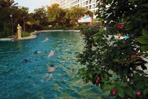A swimming pool surrounded by lush greenery and a building in the background. - Aizhihai (Beihai)