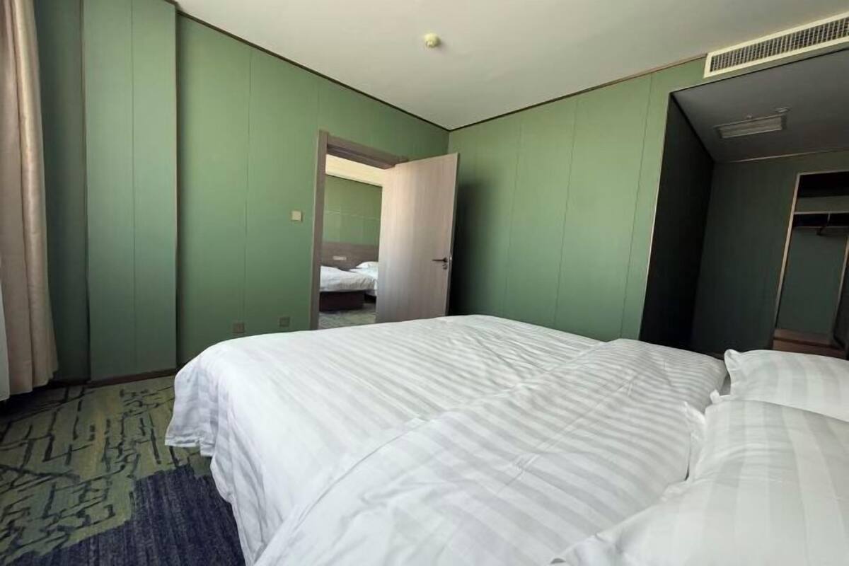 A hotel room with a bed, a mirror, a door, and a carpet.