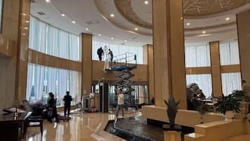 Un'ampia hall con una scalinata centrale, grandi finestre e una reception.