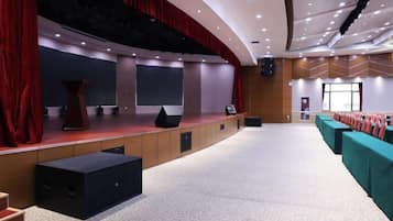 A conference room with a stage, seating, and a large screen.