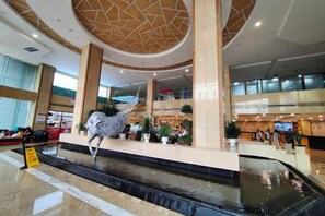 A spacious lobby with a central water feature, multiple levels, and a modern architectural design.