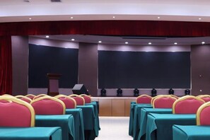 A conference room with rows of chairs, a podium, and a large screen. - Xiyu International Hotel (Urumqi)