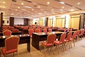A conference room with multiple tables and chairs, a projector screen, and a large window. - Xiyu International Hotel (Urumqi)