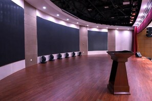 A spacious hall with a wooden floor, a podium, and large black panels on the walls. - Xiyu International Hotel (Urumqi)