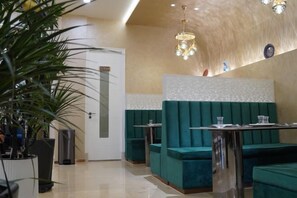 A hotel lobby with green seating, a reception desk, and a door. - Xiyu International Hotel (Urumqi)
