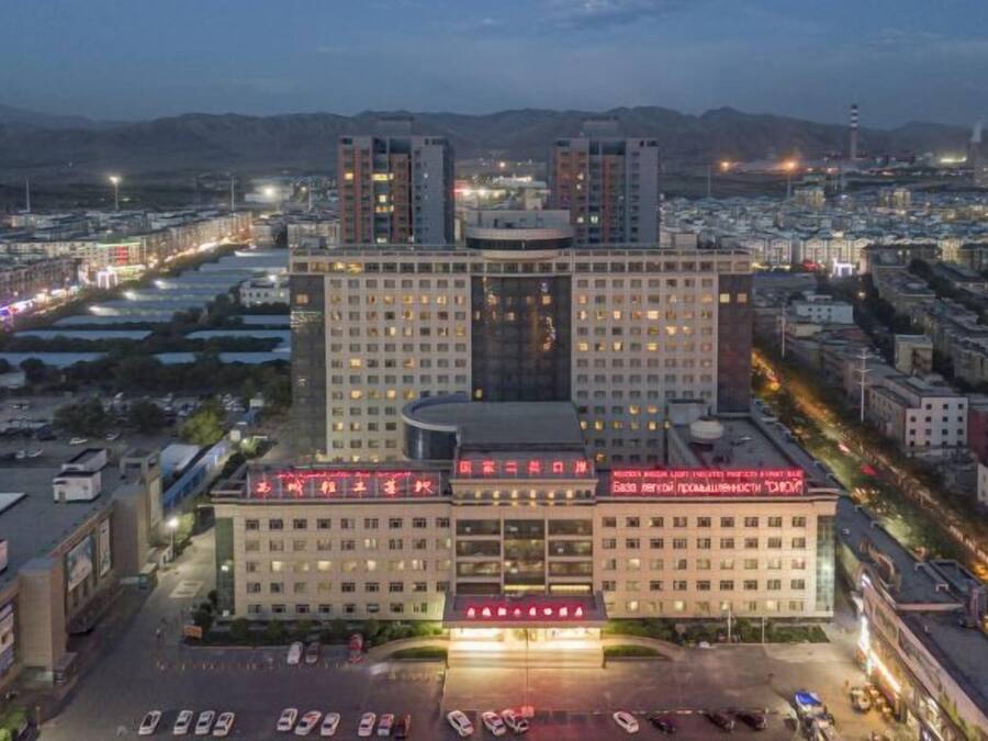 A multi-story hotel with a central atrium, surrounded by parking and roads.