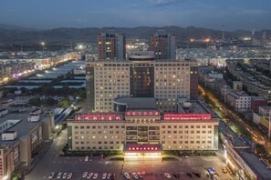 Un hotel de varios pisos con un atrio central, rodeado de estacionamiento y carreteras.