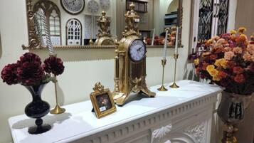 A white mantelpiece with a clock, vases with flowers, and a framed picture.