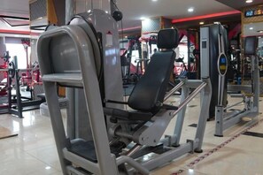 Une salle de sport équipée de divers appareils d’exercice, notamment une machine pour les exercices des jambes et une machine pour les exercices de la poitrine.