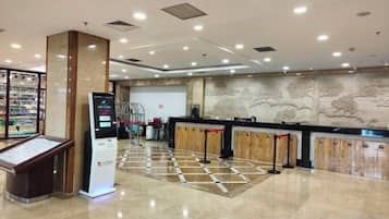 A hotel reception area with a kiosk, a counter, and a decorative wall.