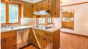 A kitchen with wooden cabinets, a stainless steel dishwasher, and a central island.