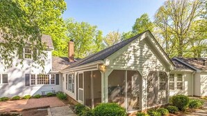 A two-story house with a covered porch and a brick pathway leading to the entrance.