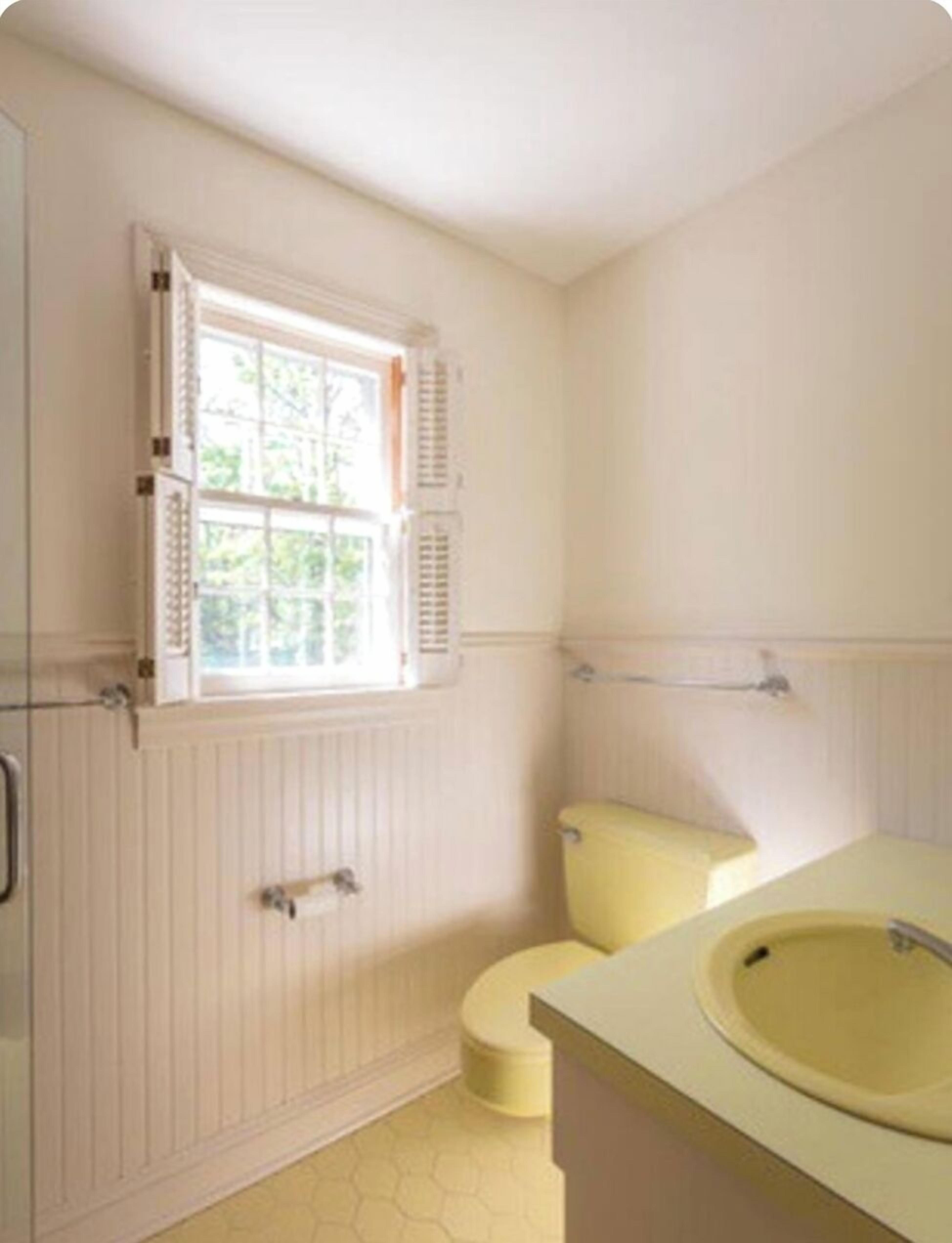 A bathroom with a window, a toilet, and a sink.
