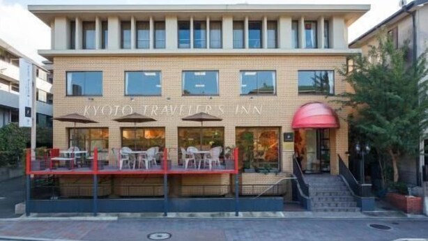 A building with a sign reading 'KYOTO TRAVELER'S INN' and a covered outdoor seating area with tables and chairs. - Kyoto Travelers Inn (Kyoto)