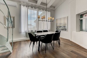 Un espace repas comprenant une table et des chaises, un lustre et un escalier.