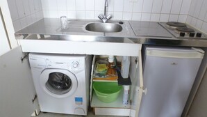 A compact kitchen with a built-in washing machine, a sink, and a small refrigerator. - Appartement Plain-pied Proche Thermes Parking Privée (Bagnères-de-Bigorre)