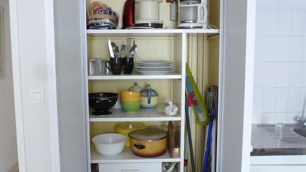 A kitchen with white cabinets, a coffee maker, a blender, and various kitchen utensils. - Appartement Plain-pied Proche Thermes Parking Privée (Bagnères-de-Bigorre)